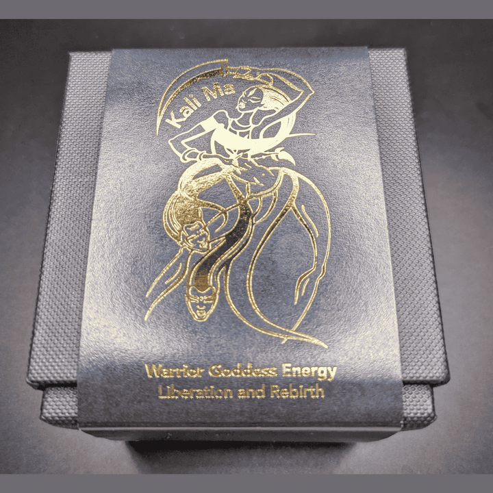 Decorative candle box with gold embossed design and text on a dark background